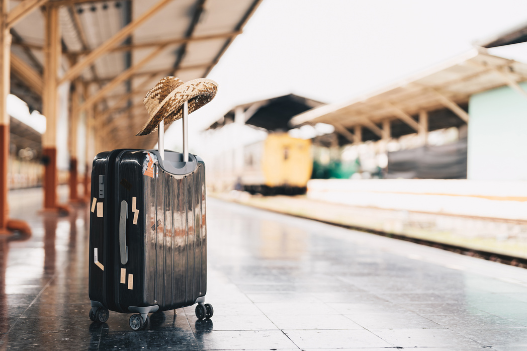 Summer travel concept. Luggage with 
straw hat on train stat